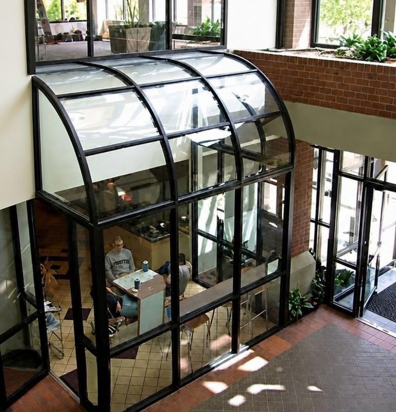 Glass-enclosed cafe seating pavilion within the atrium