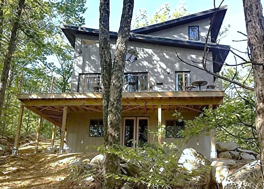 Wooded rear exterior with elevated deck and walk-out basement
